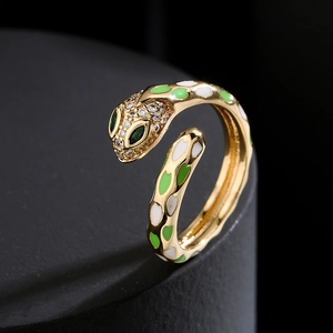 Vintage gold snake ring with white and green enamel scales on a black pedestal