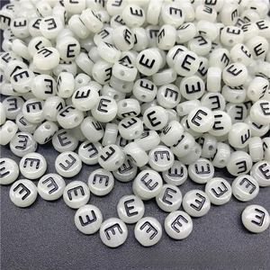 Close-up of white acrylic letter E beads for DIY jewelry with a central stringing hole