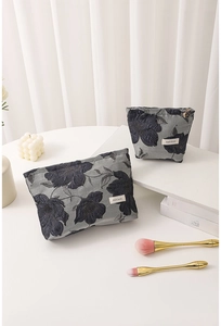 Close-up of jacquard toiletry bags with dark blue floral embroidery and white labels