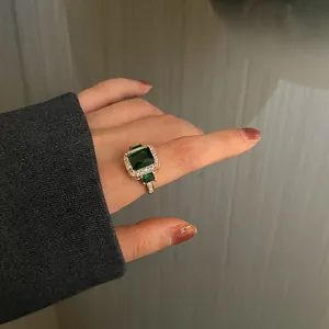 Macro detail of vintage gold-plated ring with emerald-cut green stone and pavé accents
