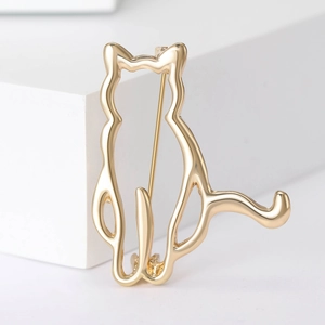 Detail of a minimalist gold cat brooch with elegant hollow lines on white background