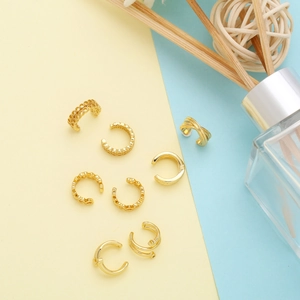 Detailset mit 8 goldenen Ohrmanschetten mit Waben- und Herzdesign auf pastellfarbenem Grund
