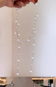 Detail of elegant glass pearl necklace featuring mixed sizes on a silver metal chain