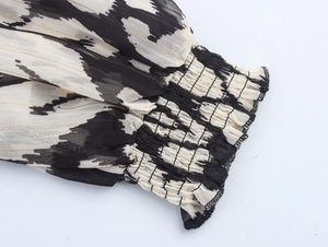Detail of smocked elastic cuffs on black and white chiffon dress with gold metallic threads