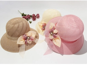 Detailed close-up of straw sun hats with floral mesh ribbons in pink, beige, and khaki
