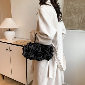 Detail of elegant black silk evening bag with 3D rose flower design and pearl handle