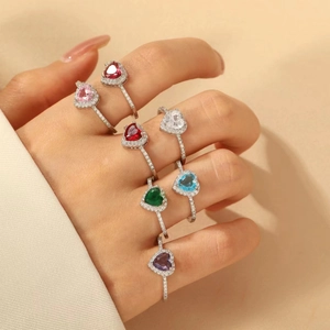 Close-up of hand wearing six colorful heart-shaped zircon rings in silver finish