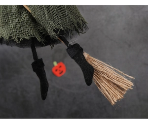 Close-up of witch doll's dark green burlap skirt and straw broom for Halloween party