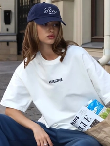 Dettaglio della t-shirt in cotone bianco con stampa e cappellino ricamato blu navy
