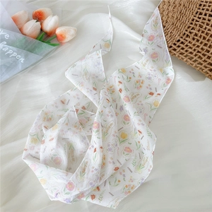 Close-up of lightweight white floral silk scarf with colorful prints on a textured fabric