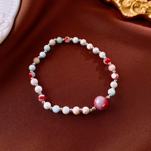 Detail of beaded Shoushan stone bracelet with red and green beads on a vintage fabric