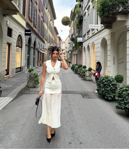Détail de l'ensemble gilet en maille blanc et jupe plissée en mousseline sur rue