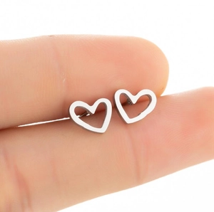 Steel hollow heart stud earrings held in hand to showcase minimalist size and detail