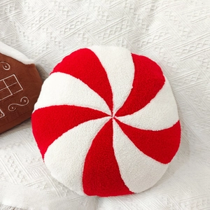 Detail of round red and white peppermint candy plush pillow with soft sherpa texture