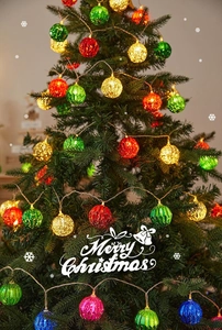 Close-up of glowing colorful hollow sequin LED ball string lights on Christmas tree