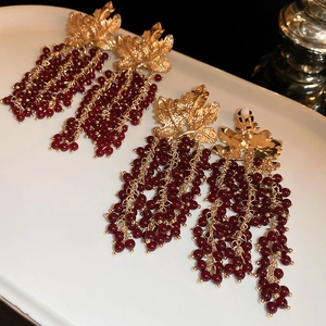 Detailed view of vintage gold leaf earrings with long dark red beaded tassel fringe