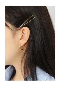 Close-up of elegant gold minimalist hair clip and small round earrings on model