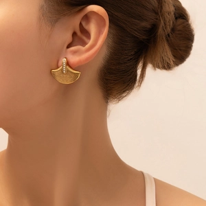 Detail shot of a fan-shaped gold plated titanium steel earring with white sparkling stones