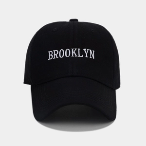 Close-up of white Brooklyn embroidery on a black cotton twill baseball cap with fine texture