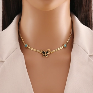 Detail of gold snake chain with black butterfly pendant and turquoise gemstone accents