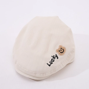 Dettaglio del ricamo LUCKY e del motivo orso sul berretto in tela beige per bambini