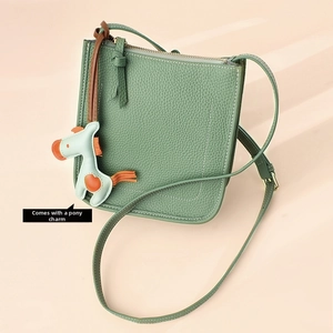 Minimalist dark green pebble leather bucket bag with contrast stitching and horse charm