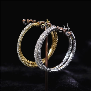 Close-up of oversized gold and silver hoop earrings encrusted with sparkling rhinestones