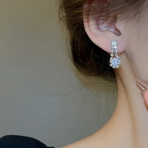 Macro shot of silver teardrop earrings with crystals worn by model for elegant style