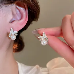 Elegant gold butterfly pearl earrings with sparkling rhinestones and white enamel inlay