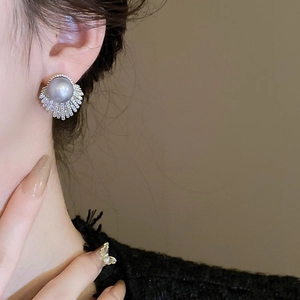 Macro view of grey pearl stud earrings with zircon fan border on a model's ear