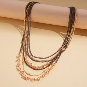Detail of layered necklace featuring brown chains and amber crystal beads on golden links