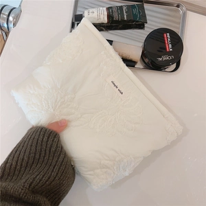 Close-up of quilted white lace pouch with simple wish embroidery for cosmetics