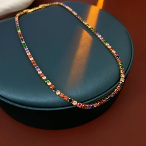 Exquisite gold-plated necklace with colorful round zircons on a green luxury jewelry stand