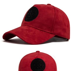 Dettaglio cappellino da baseball rosso in pelle scamosciata con toppa circolare nera