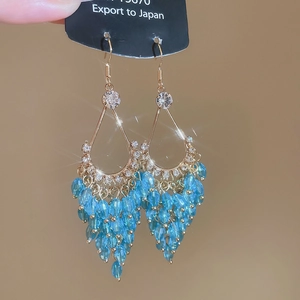 Detail of gold water drop earrings with white rhinestones and blue crystal tassels