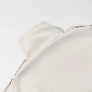 Detailed close-up of the high neck collar and shoulder on a beige double-breasted trench coat