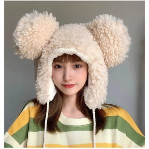 Detail of plush beige earflap hat featuring large round ears and braided chin straps