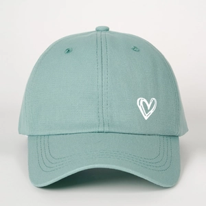 Detailed close-up of white heart embroidery on a sage green cotton baseball cap