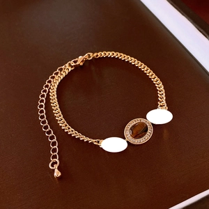 Close-up of gold-plated Cuban chain bracelet with oval tiger eye stone and zircons