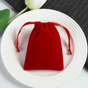 Macro shot of red velvet drawstring pouch for jewelry storage on a white plate