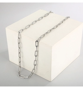 Detailed view of silver rectangular link chain draped on a white geometric block