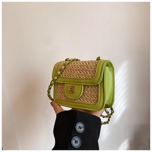 Detail of green straw flap bag with golden flower buckle and elegant chain strap