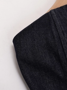 Makroaufnahme von dunkelblauem Denim-Stoff mit sichtbarem Köperbindungsmuster am Kleidungsstück