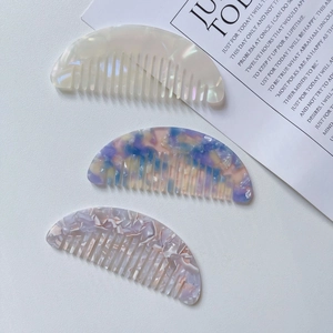 Detailed view of three mini acetate hair combs in marble and floral patterns
