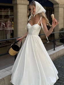 Détail de robe longue en coton blanc avec fines bretelles et buste plissé dans la rue