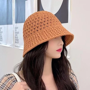 Detail view of the hollow-out woven texture on a brown-orange summer straw bucket hat