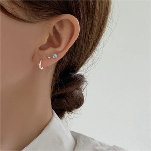 Close-up of 925 sterling silver ear studs featuring a green enamel smiley face design