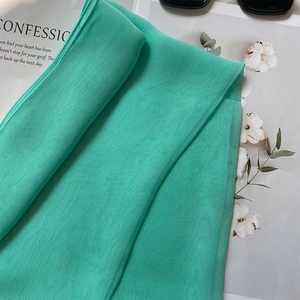Detailed macro view of mint green silk scarf fabric showing lightweight and airy texture