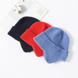 Flat lay of knit winter earflap hats in navy blue, bright red, and sky blue colors