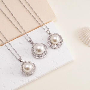 Eleganti collane di perle con vari pendenti in zircone su un vassoio di pietra naturale
